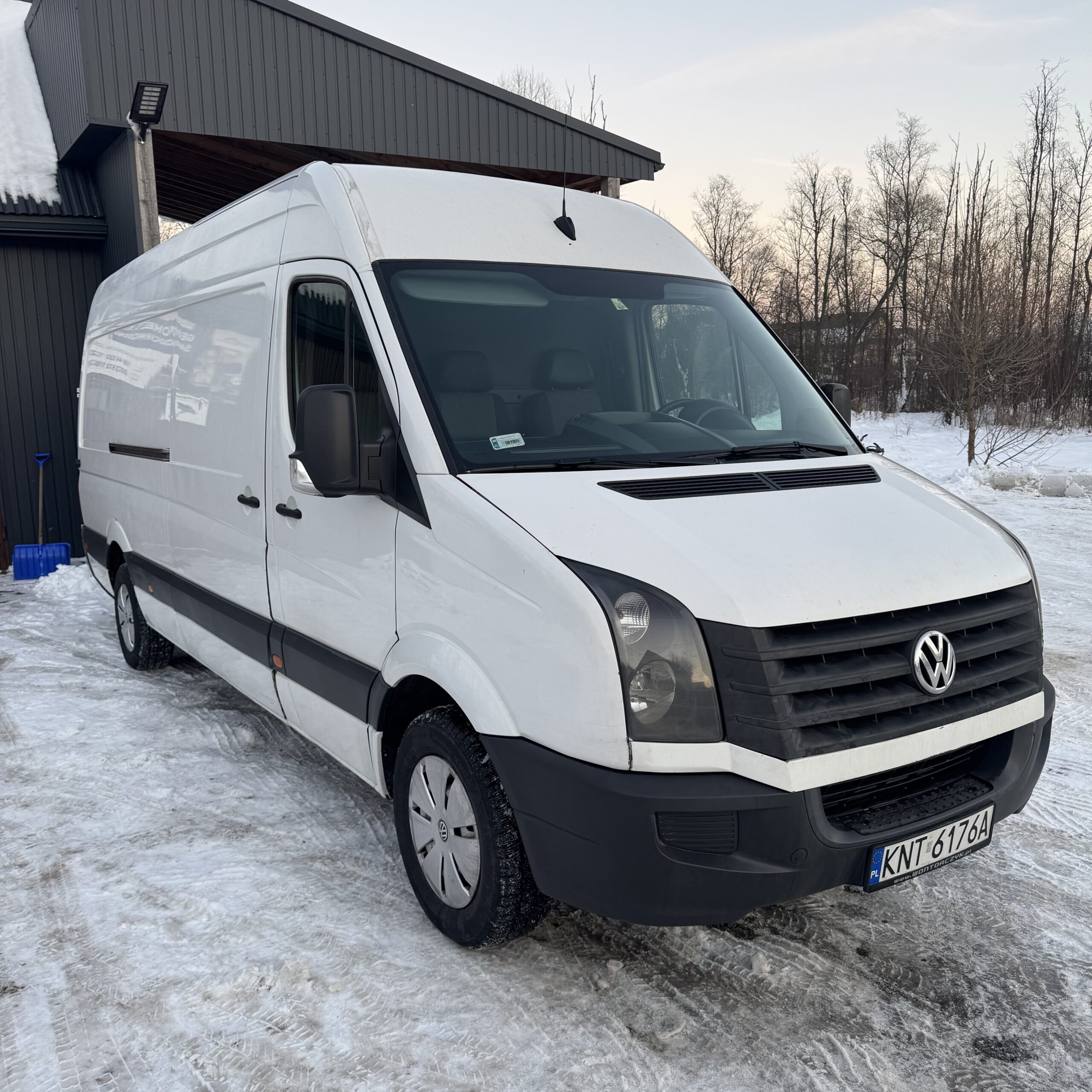 Biały Volkswagen Crafter stojący na ośnieżonym podjeździe, widoczny z przodu i boku.